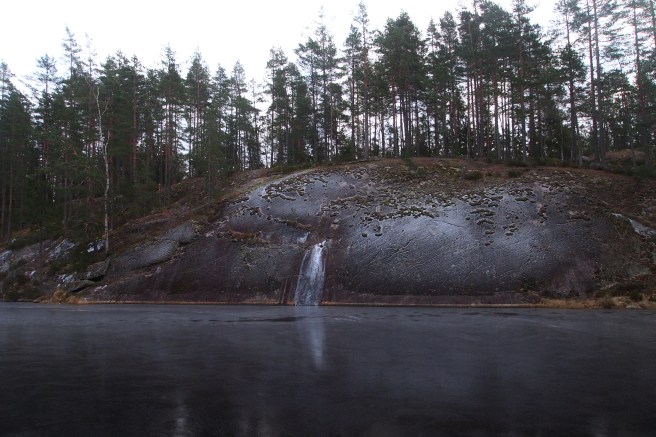 Frosty rock with a frozen lake and a waterfall